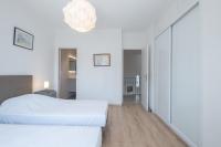 a white bedroom with two beds and a chandelier at SERRENDY Calm family house with swimming pool in Antibes