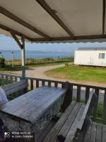 a picnic table on a deck with a view of the ocean at Camping du phare d opale p48 in Le Portel