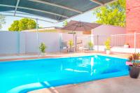 a blue swimming pool with an umbrella and a house at K - Town Hotel in Katherine