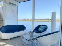 a large tub and two chairs in front of the water at Homeboat Glamping in Nieuwpoort