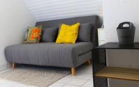 a gray couch with yellow pillows in a living room at Le studio du dolmen à Plouharnel in Plouharnel
