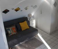 a living room with a black couch with a yellow pillow at Le studio du dolmen à Plouharnel in Plouharnel