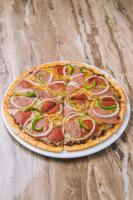 a pizza with pepperoni and green peppers on a table at Zuri Resort in Coron