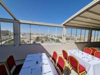 a room with two tables and chairs and windows at Hotel Delphin-Nouadhibou in Nouadhibou