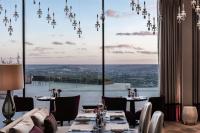 Un comedor con mesas y sillas y un gran ventanal. en Royal Champagne Hotel & Spa, en Champillon