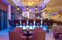 アウクスブルクにあるLeonardo Hotel Augsburgの椅子とテーブルのあるレストランのバー