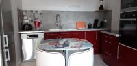 a kitchen with red cabinets and a glass table at Triplex tout confort, plein centre ville Bauge en Anjou in Baugé