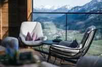 Dos sillas y una mesa en un balcón con vista. en Boutiquehotel Blaue Burg Falkenstein, en Pfronten