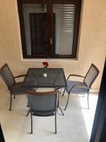 a glass table with chairs and a vase with a flower on it at Apartman ANA in Vrlika