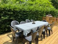 a table and chairs on a wooden deck at Océan à 10 mn, maison avec piscine, bar et babyfoot in Saint-Paul-en-Born