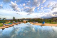 a large swimming pool with blue chairs and a cloudy sky at Naivasha Kongoni Lodge - Lakefront Getaway in Naivasha