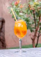 een oranje drankje met een rietje in een glas op tafel bij Hôtel au Heimbach in Lembach