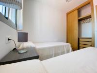 a bedroom with two beds and a table with a lamp at Apartamentos Turísticos Santo Rostro in Chipiona