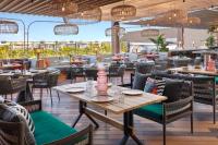 Un comedor con mesas y sillas y un restaurante. en Tribe Bali Kuta Beach, en Kuta