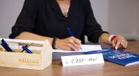 a woman sitting at a table writing on a piece of paper at Campanile Nancy Centre - Gare in Nancy