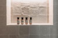three bottles of essential oils sitting on a shelf in a bathroom at HIGHSTAY - Luxury Serviced Apartments - Le Marais in Paris