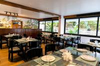 uma sala de jantar com mesas, cadeiras e janelas em Aloha Holiday Resort em Baga