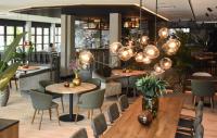 Un restaurante con mesas y sillas de madera y luces. en Hotel Restaurant De Zwaan, en Raalte