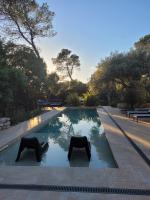 a pool with two black chairs in a garden at La Villa Kallisté in Vacquières