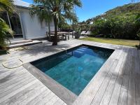 a swimming pool on a wooden deck next to a house at Nice 2 bed-rooms villa at Saint Barth in Saint Barthelemy
