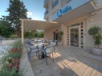 Un patio con mesas y sillas frente a un edificio. en Hotel Idila Budva, en Budva