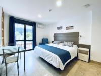 a bedroom with a large bed with a desk and a window at Hotel Apartamentos Marina Luz in Chipiona