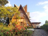 Una casa de madera con flores delante de ella. en Chalet Ecoturismo La Nohelia, en Jericó