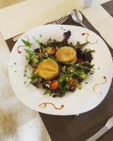 un plato de comida con una ensalada en una mesa en Logis Hôtel Le Cygne, en Le Bugue