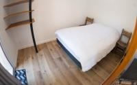 a small bedroom with a bed and a wooden floor at Longère pierres&#47;modernité proche mer&#47;la guittière in Talmont
