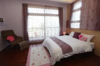 a bedroom with a bed and a chair and windows at Jing Xiang Hua Nong B&amp;B in Dongshan