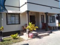 a house with a palm tree in front of it at Chiloto Guest House in Kasane
