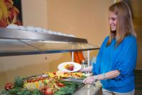 a woman standing next to a buffet of food at Rosen Inn Closest to Universal in Orlando