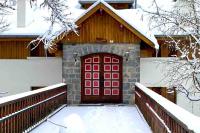 a red garage door with snow on the ground at Valberg 8 couchages cocon familial in Guillaumes
