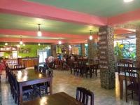 a restaurant with tables and chairs in a room at Tree Tops River Huts in Khao Sok