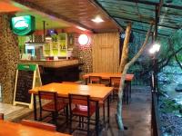 a restaurant with wooden tables and a fishtank at Tree Tops River Huts in Khao Sok