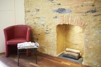 a red chair sitting next to a stone fireplace at Logis Hôtel Duquesne in Nantes