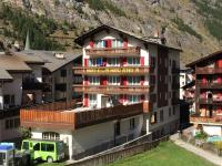a building with a green truck parked in front of it at Hotel Rhodania in Zermatt