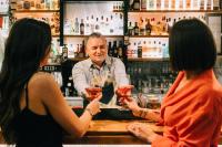 duas mulheres conversando com um barman em um bar em Telesilla Hotel em Kontokali