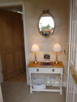 a room with a table with two lamps and a mirror at Garden Suite in Rhuddlan