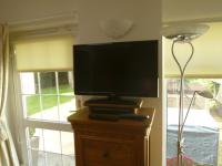 a flat screen tv sitting on a wooden stand next to a window at Garden Suite in Rhuddlan