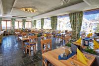 a restaurant with wooden tables and chairs and windows at Alpenhotel Rieger in Mittenwald