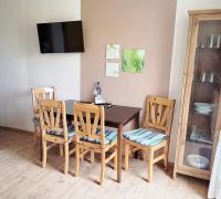 a dining room table with three chairs and a television at Pension Landhaus Teichgraf in Wolgast