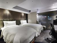 two beds in a hotel room with white sheets at The Tango Hotel Taipei FuHsing in Taipei