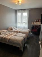 two beds in a bedroom with a window and a chair at Chambre d hote au calme in Brétigny-sur-Orge