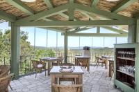 un patio con mesas, sillas y ventanas en Gallicantu Stazzo Retreat, en Luogosanto