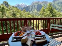 a table with plates of food on a balcony with mountains at Chalet Altus in Sainte-Foy-Tarentaise