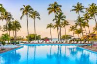 una piscina con palmeras y el océano en La Creole Beach Hotel &amp; Spa, en Le Gosier