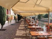 eine Reihe von Tischen und Stühlen mit Sonnenschirmen auf einer Terrasse in der Unterkunft Ankerhof Hotel in Halle an der Saale