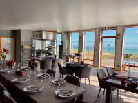 a dining room with tables and chairs and the ocean at The Cliffs Seaside Lodge in Tuatapere