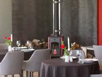 a dining room with tables and chairs and a wood stove at The Cliffs Seaside Lodge in Tuatapere